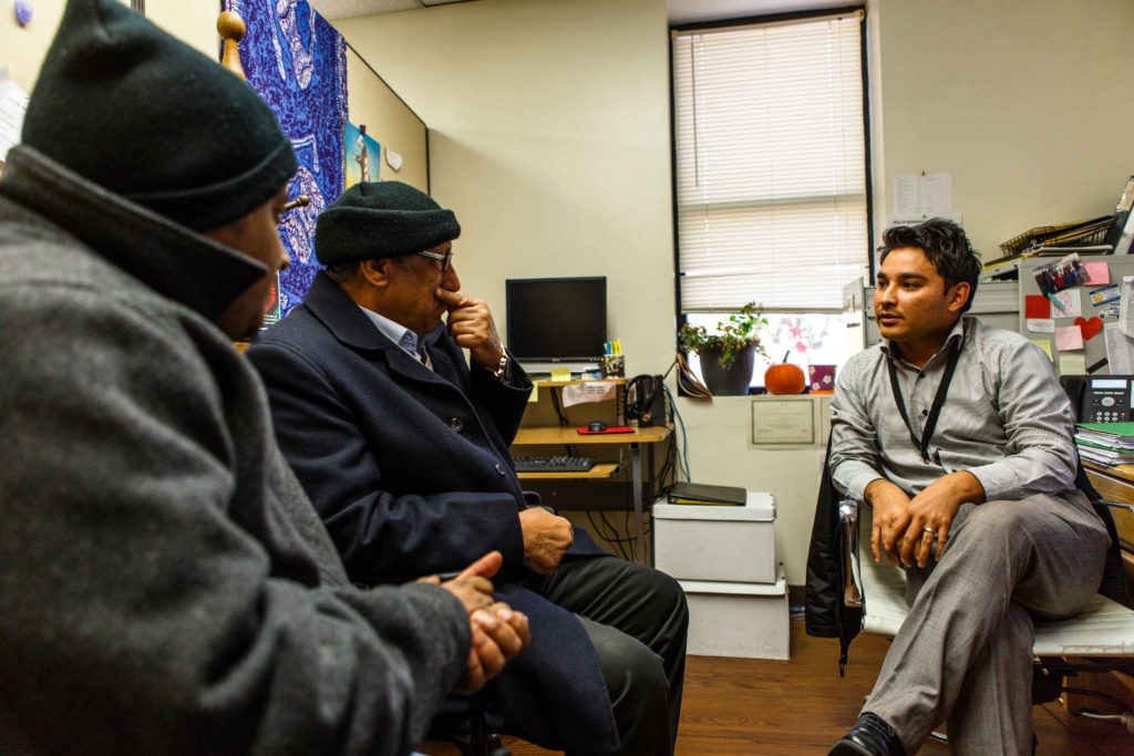 A refugee resettlement caseworker helping two recently resettled refugees at his office in Baltimore
